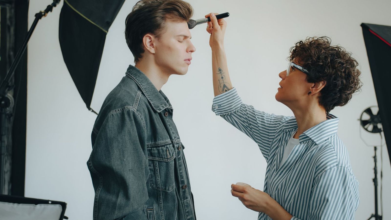 Make-up-Artistin schminkt ein Model beim Studio-Fotoshooting